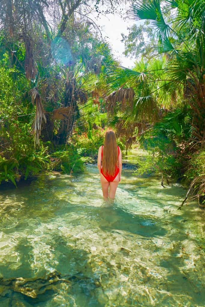 A woman wades into the water underneath a canopy of trees at Juniper Springs.