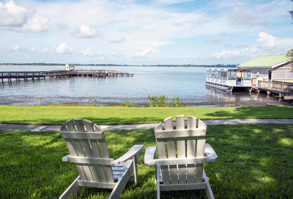 Two chairs on a green lawn overlooking Dora lake and piers.