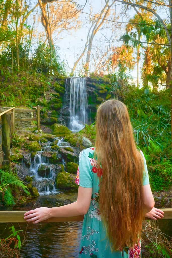 A woman has her back to the camera as she gazes at one of the three waterfalls at Rainbow Springs.
