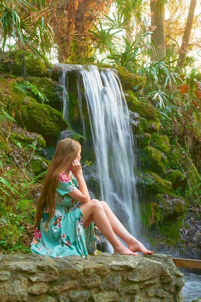 woman in green dress sitting with a waterfall in the background