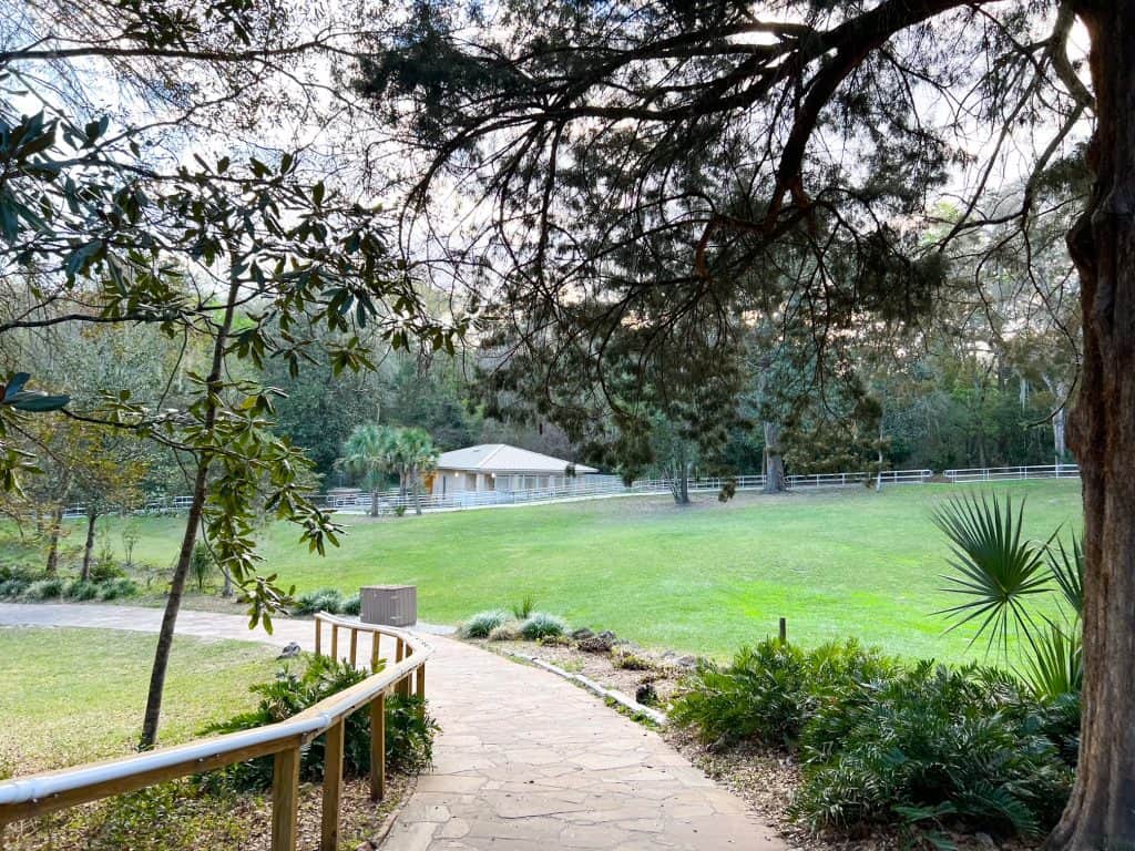 A walkway and paved path guides people down a green hill and toward the camping area that features a store and restrooms at Rainbow Springs.