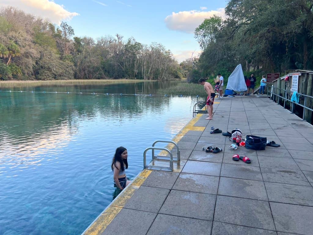 People gather at the edge of the swimming hole at Rainbow Springs, getting ready to dive into the blue water.