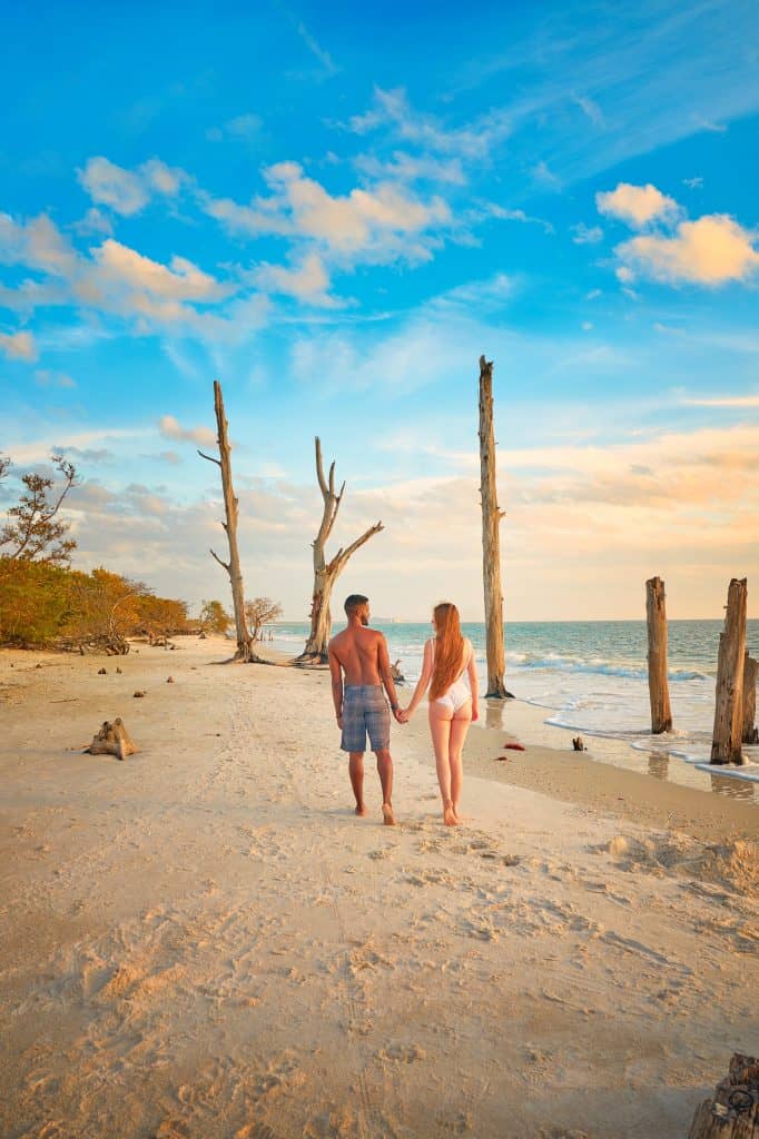 A man and woman walk hand-in-hand along the beach at Lovers Key, one of the most romantic weekend getaways in Florida.