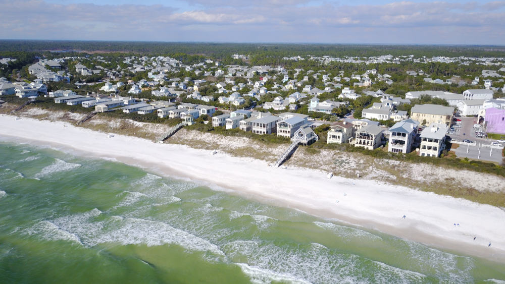 An aerial view of light-colored houses along the shore of Seaside, one of the best little beach towns for weekend getaways in Florida.