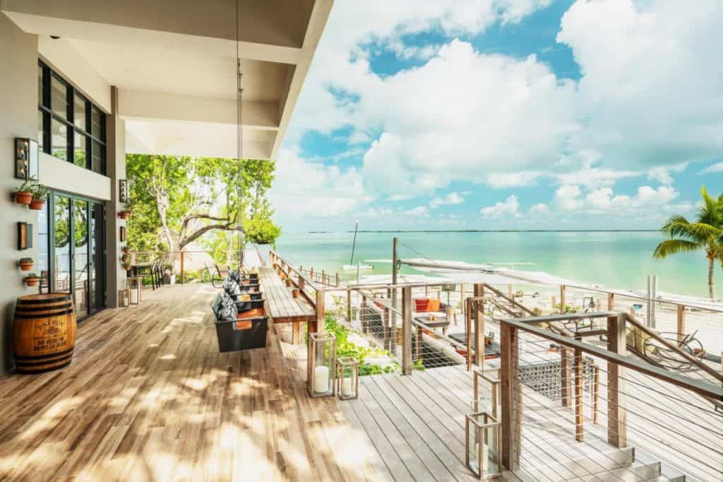 A shot of the bay-facing area at Baker's Cay, there are colorful black and orange deck chairs that face the white sand beach with turquoise waters that is just a few steps away