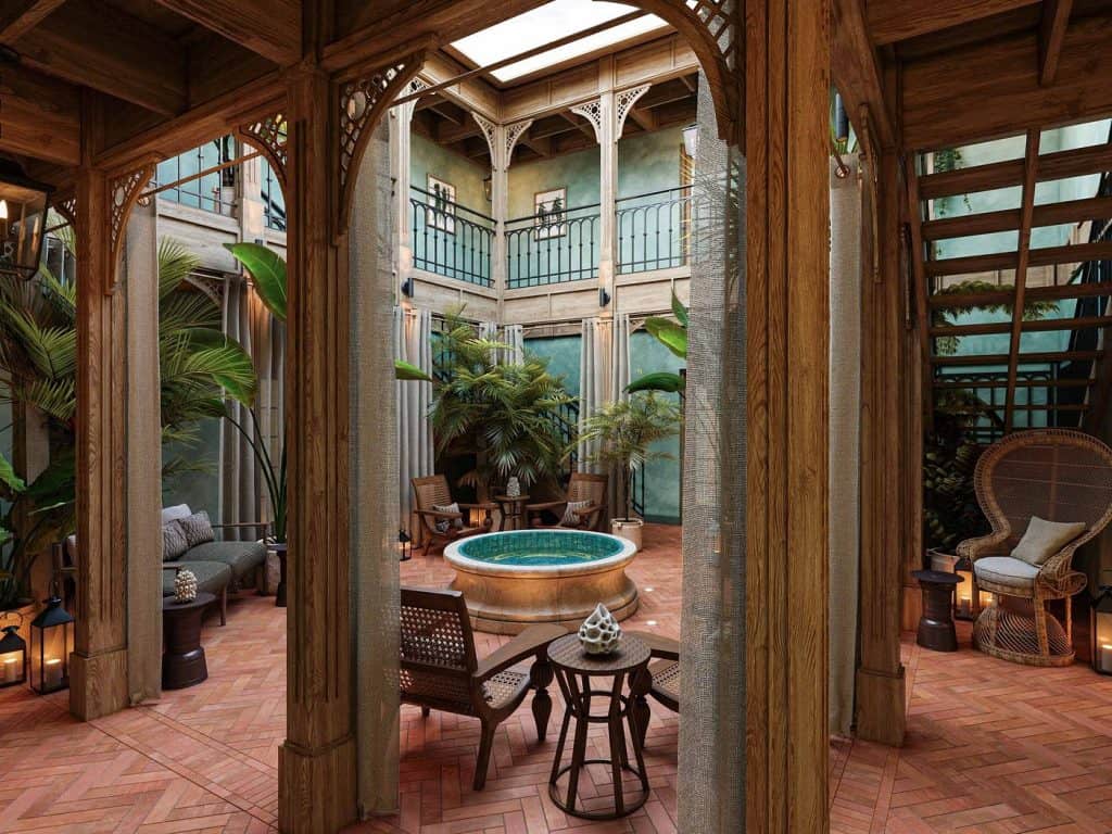 a beautiful sitting area at the resort with teal walls and copper colored brick floors, a water feature sits in the center of the room surrounded by brown rattan furniture 