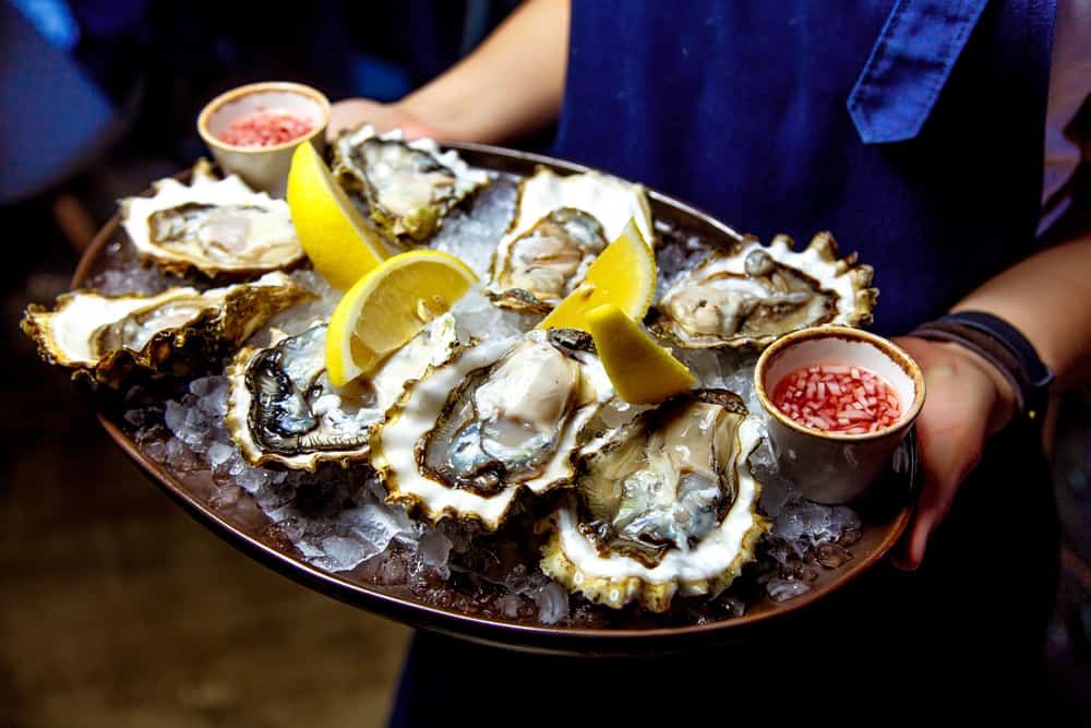 A waiter carries out a plate of raw oysters on ice: meals like these are common at the restaurants In Punta Gorda, especially if they are on the water. 