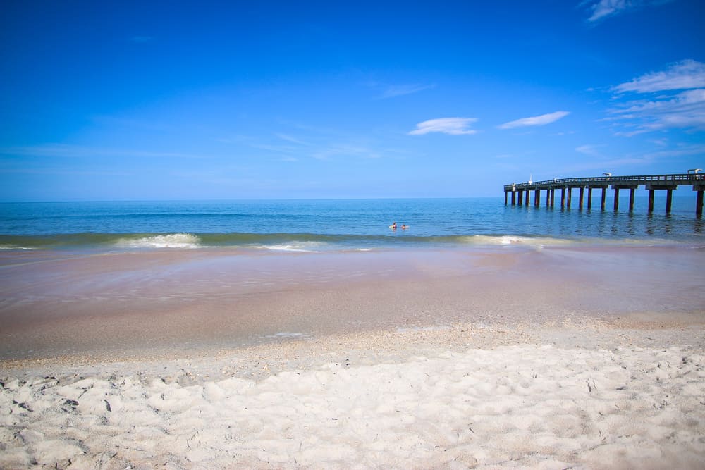 The white sands of Saint Augustine beach with a pier jutting out into the water.