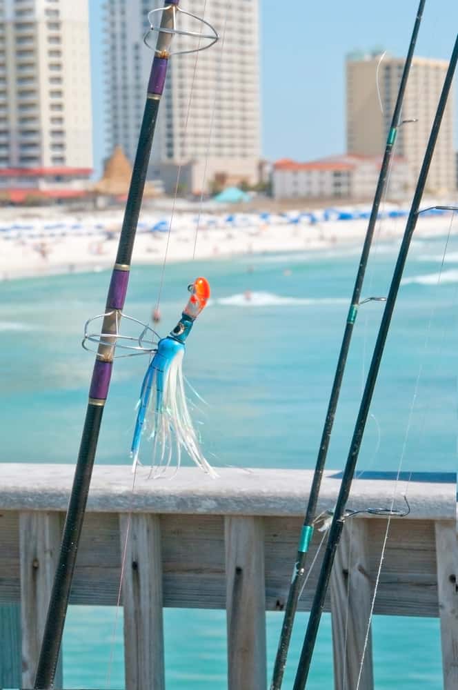 A couple of fishing rods leaning against the pier with the beach in the background.