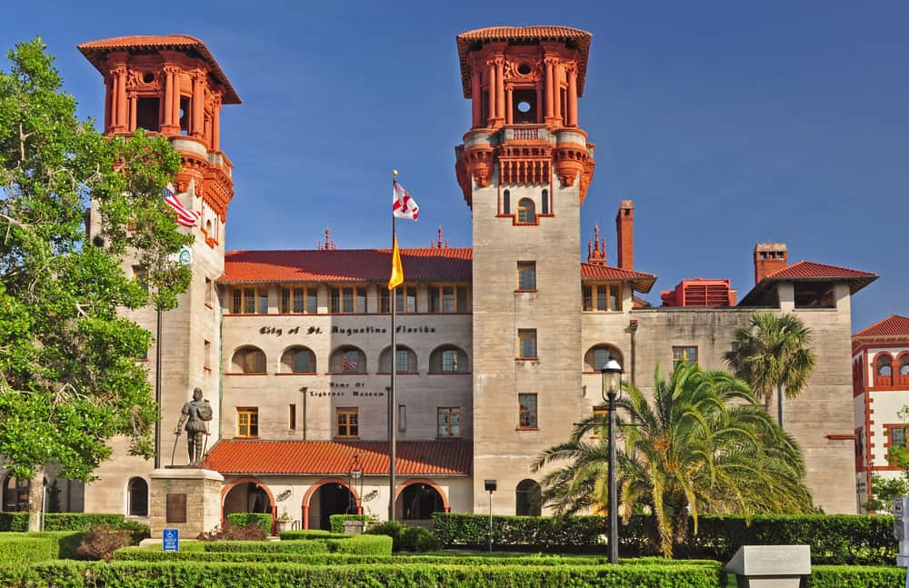 The Lightner Museum with palm trees and hedges in front.