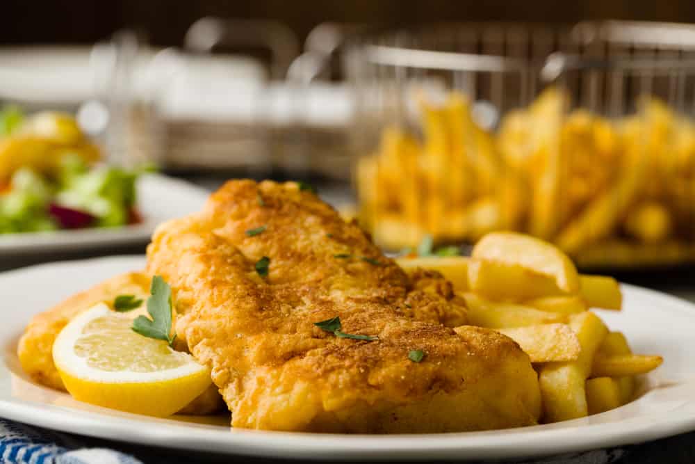 Fish and chips on a plate with a slice of lemon. 