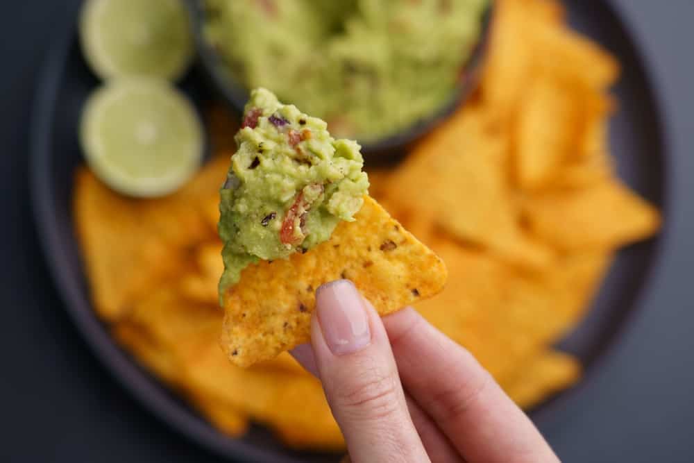 person holding a tortilla chip dipped in homemade avacado. This mexican restaurant in one of the best restaurants in Captiva