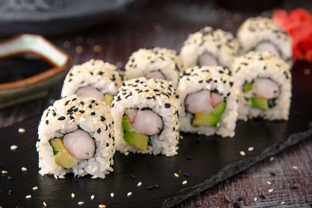 Some of the best restaurants in Daytona Beach feature seafood, like in this photo: a roll of sushi sits on a black plate and is perfectly sprinkled with sesame seasonings.
