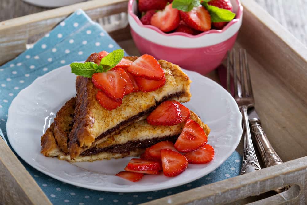 Piles of stuffed french toast and tons of strawberries sit on this plate that is delivered to a table at one of the many restaurants in Sanibel you can enjoy breakfast and brunch at. 