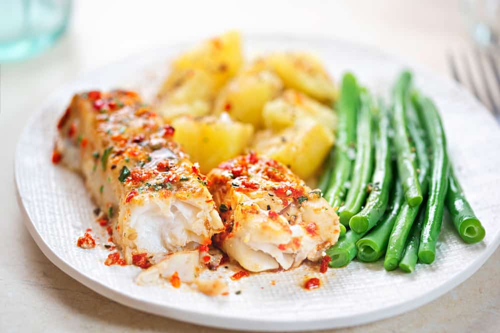 Two pieces of perfected grouper sit on this late next to potatoes and green beans: fresh seafood meals like this are common at restaurants in Sanibel! 