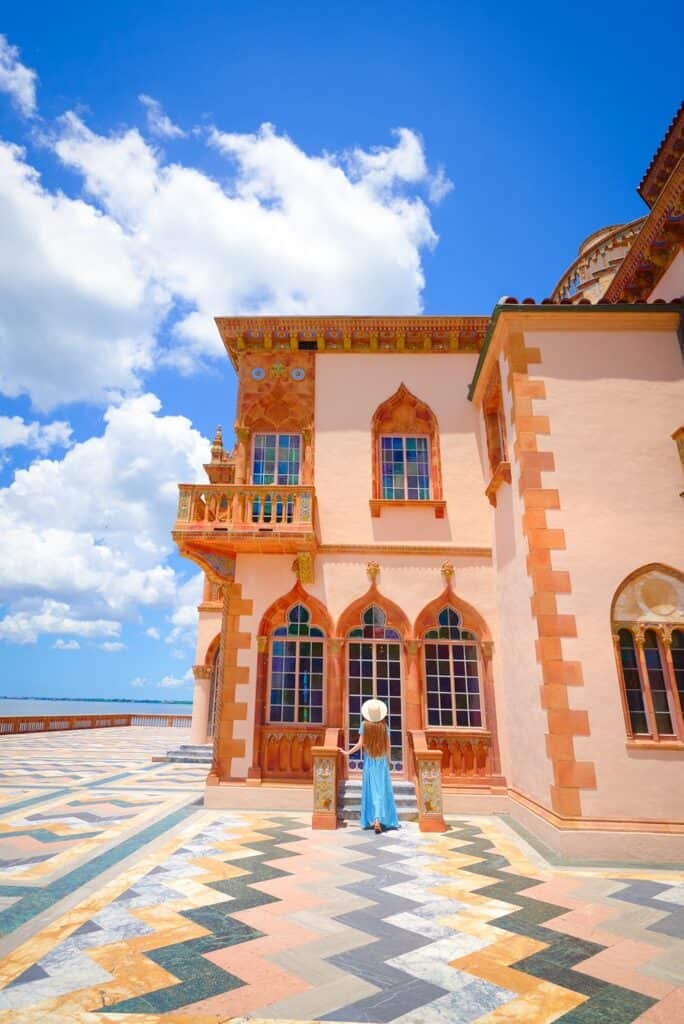 Victoria pauses at a set of stairs while looking up at the blue and purple tiles of the Ca'd'Zan Mansion at the Ringling Museum. 