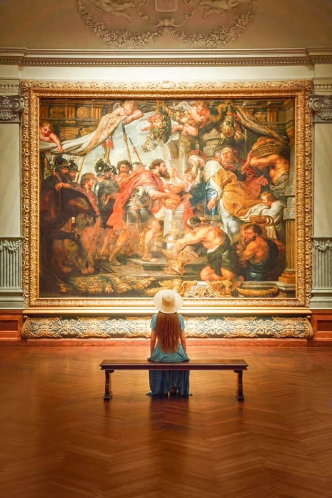 Victoria sits with her back to the camera as she gazes at a piece of an art collection at the Ringling Museum. 