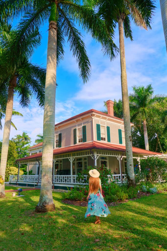 A picture of a woman in a colorful dress standing in front of a historical estate in the sunshine