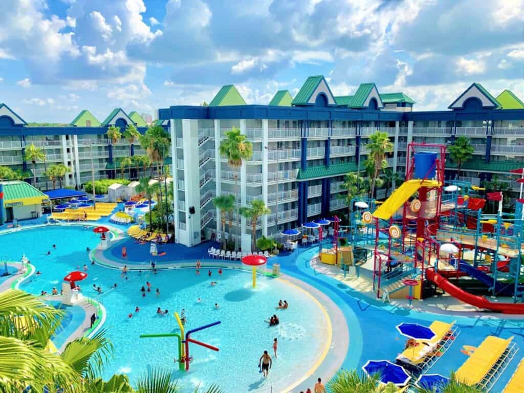 an overheard view of the water park at the holiday inn suites in Orlando, there are lots of colorful umbrellas an pool equipment, and in the background there is a tangled mess of colorful water slides 