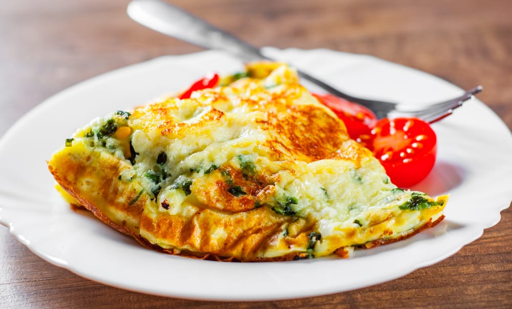 Plate with a tasty omelet and side of tomatoes.