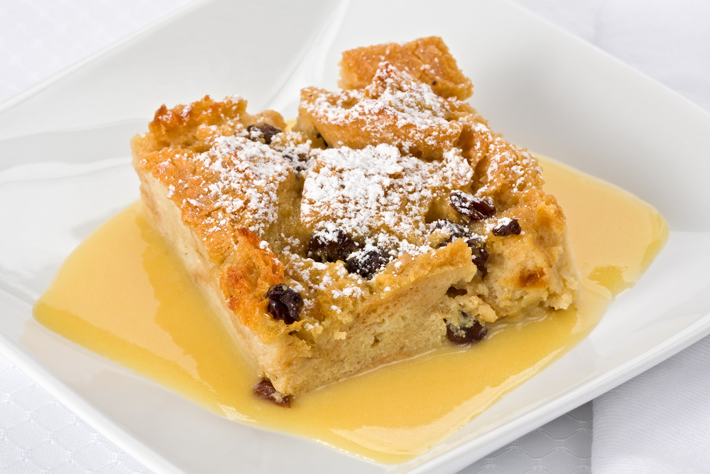 A slice of bourbon bread pudding with powdered sugar on top.