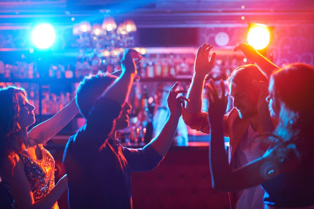 A group of people dance in neon blue and orange lights at one of the best clubs and bars in Gainesville.