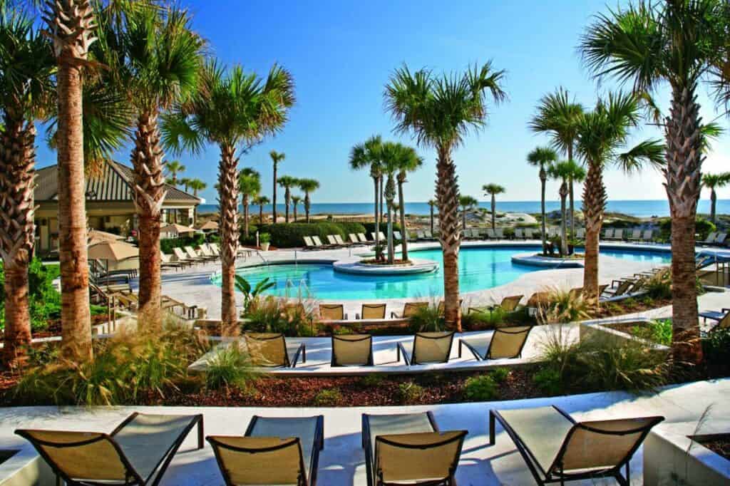 a shot of the pool area at the ritz carlton amelia island, the pool is surrounded by metal and tan pool chairs one of the best luxury hotels in Florida