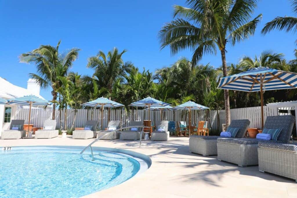 A shot of the pool area at Isla Bella Beach Resort, the furnishings are shaded by blue and white striped umbrellas