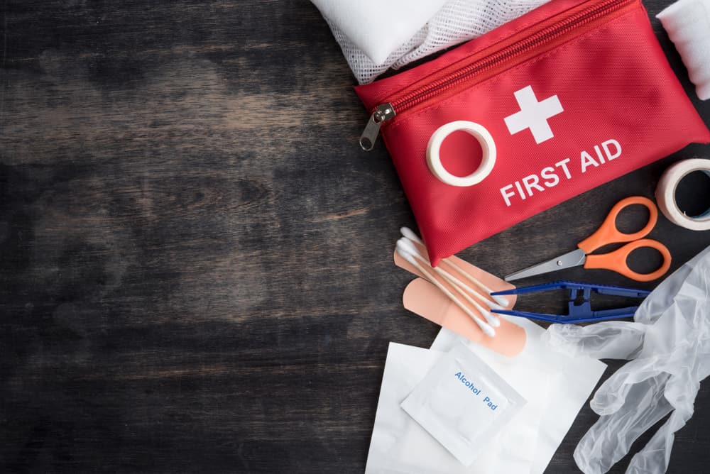 A first aid kit empties its supplies on a table, showing q-tips, bandaids, alcohol pads and more. These are perfect items to add to your hurricane preparedness list. 