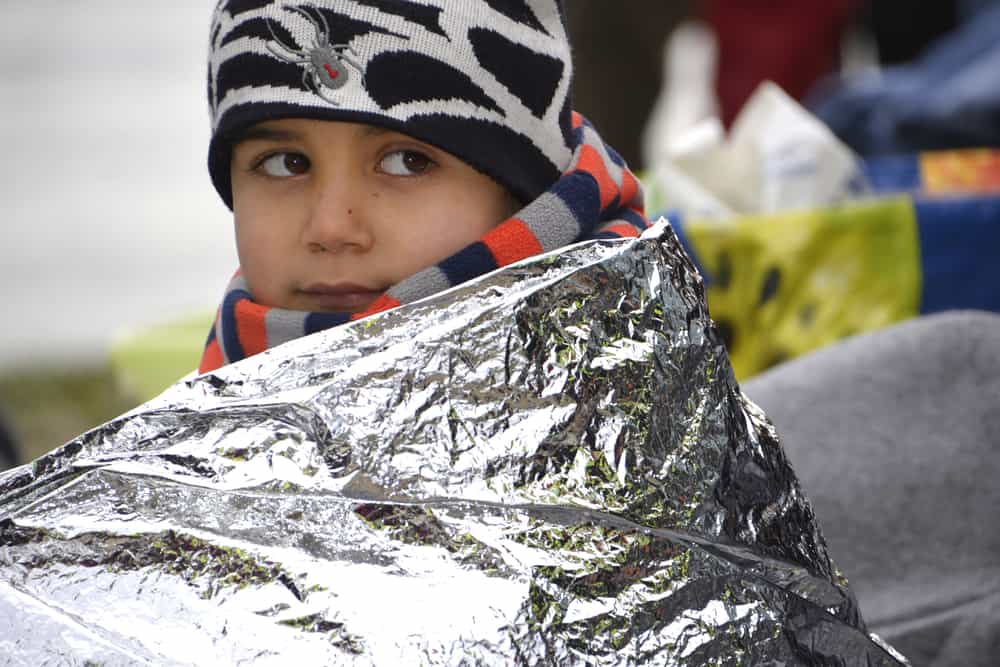 A child sits wrapped in an emergency blanket. This foil is designed to be water proof and keep us warm, which is perfect for emergencies and for our hurricane preparedness list. 