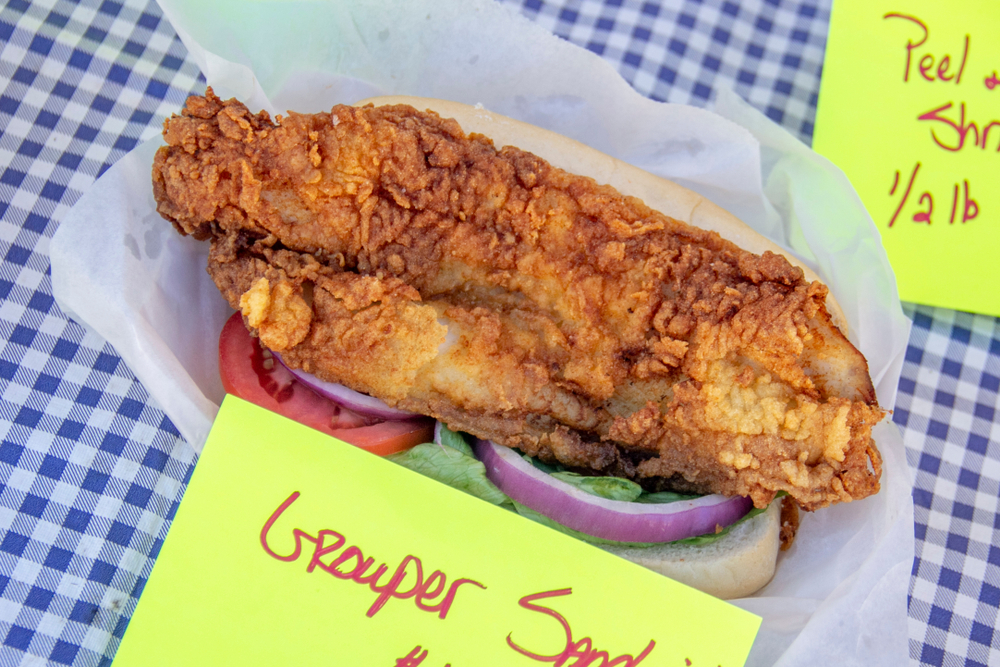 A large, fried grouper sandwich on a gingham tablecloth, like those served at Dockside Dave's seafood restaurant in Madeira Beach, FL