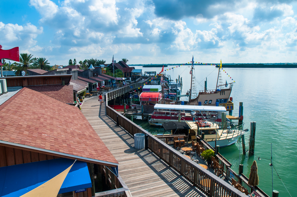 A view of the docks alongside John's Pass Village and Boardwalk, where a pirate ship, with colorful flags, sits ready to board.