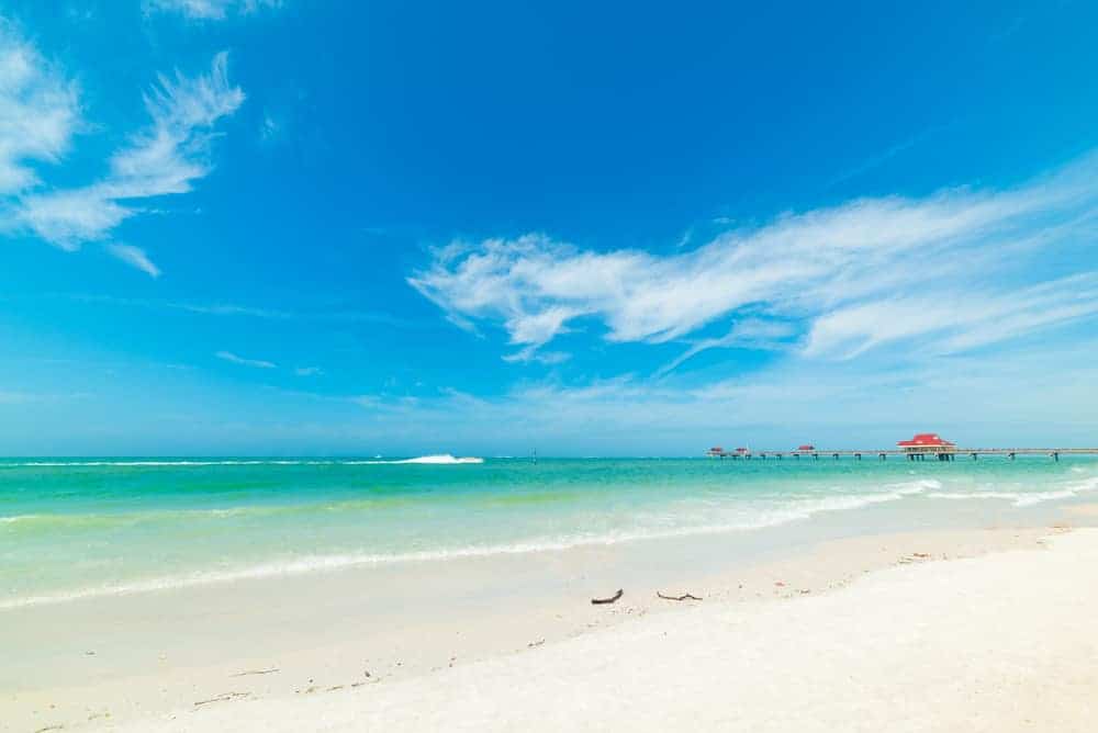 A fishing pier extends into emerald waters at Clearwater Beach, one of the best places to visit near Treasure Island.