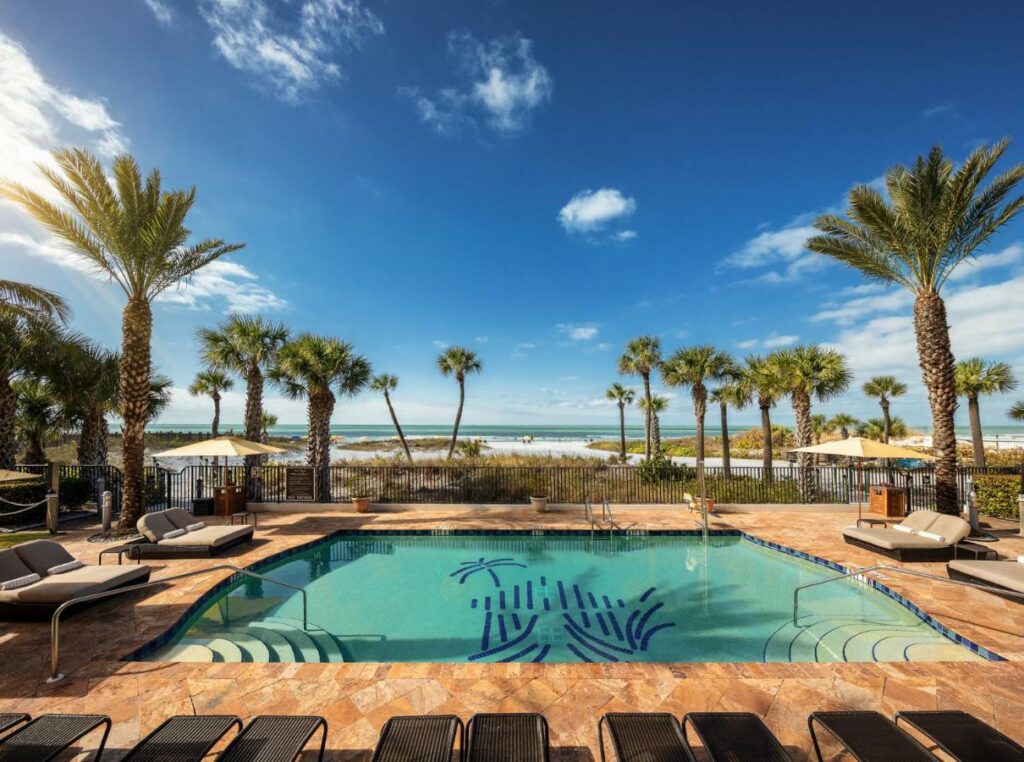 A picture of the Hyatt Residence club's pool area, lots of palm trees are mid sway in the breeze and the white sandy beach glistens in the background 