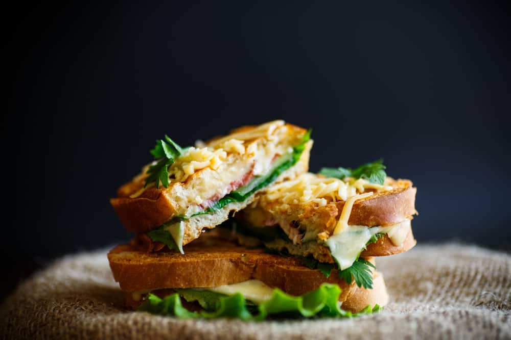 A breakfast sandwich at one of the places that services breakfast in Saint Augustine sits on a table with perfectly toasted sourdough, eggs, lettuce, and more. 