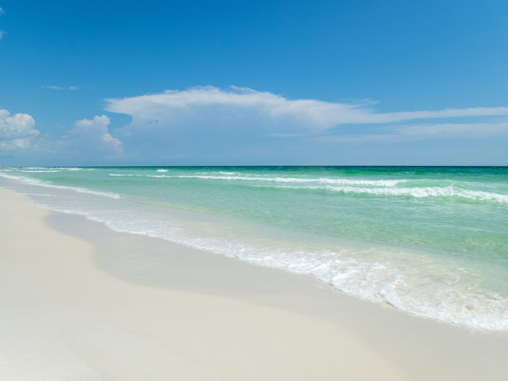 Emerald-colored waves wash up on the clear sand of Henderson Beach State Park, one of the best beaches in Destin.