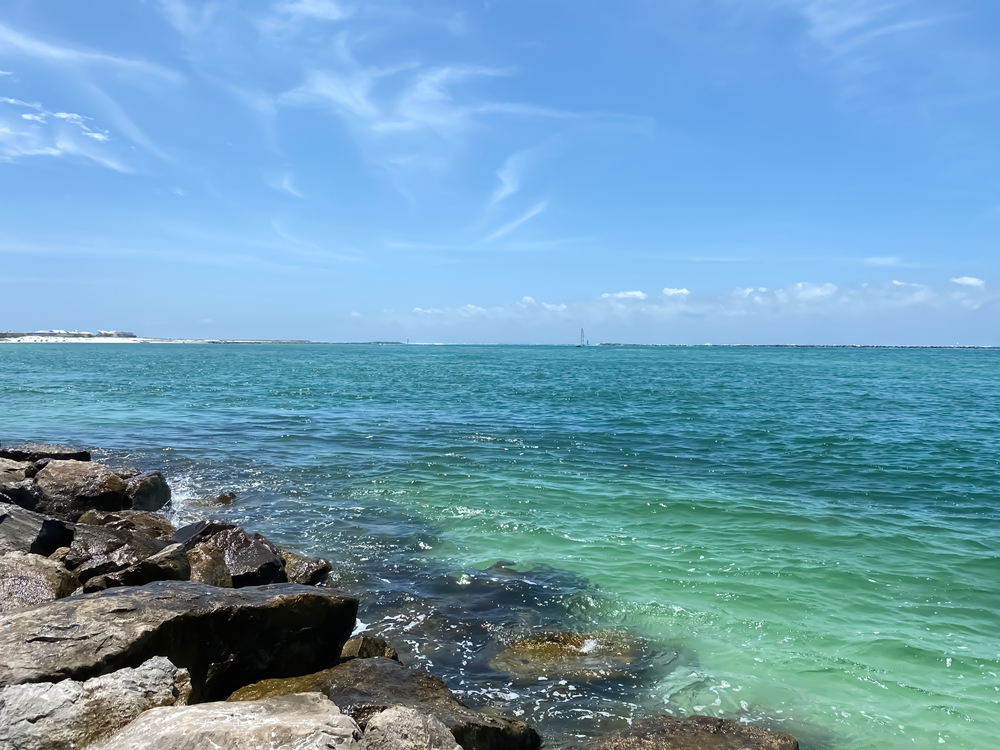 The rocky shore on a sunny day at Norriego Point, which has some of the clearest water of all the beaches in Destin, FL.