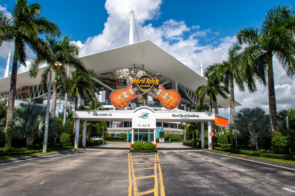 Entrance to the Hard Rock Stadium with a palm tree lined street.