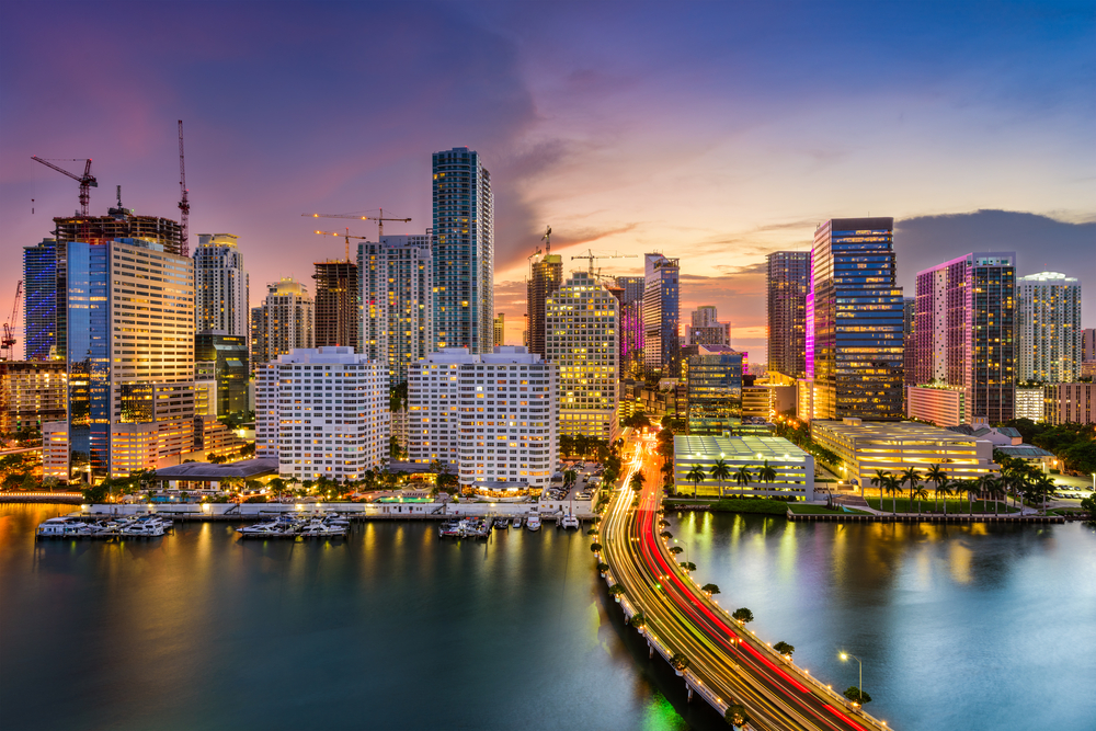 A long exposure, drone photo of Miami at night, with cars crossing the Key Biscayne bridge.