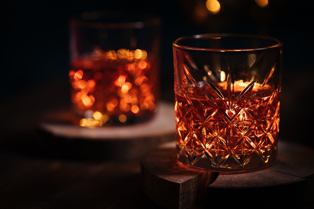 A closeup photo of cut glass cocktail glasses with a dark background.