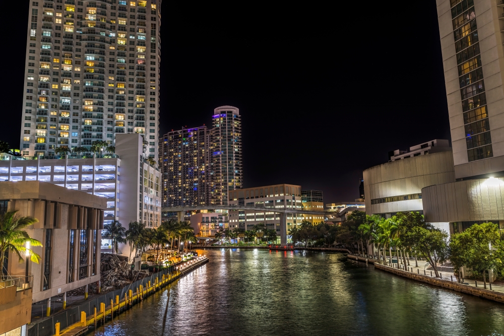 The river walk at night, with tall buildings on either side, where kayaking or paddle boarding is one of the best things to do in Miami at night.