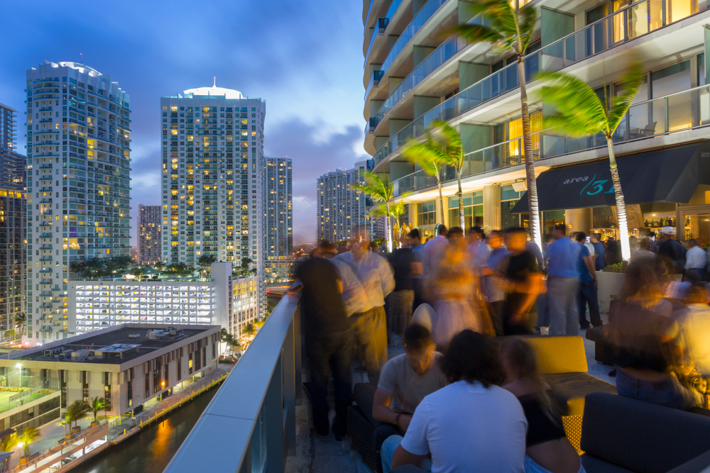 A crowd of people enjoying drinks on a rooftop bar in Miami, one of the best things to do in Miami at night.