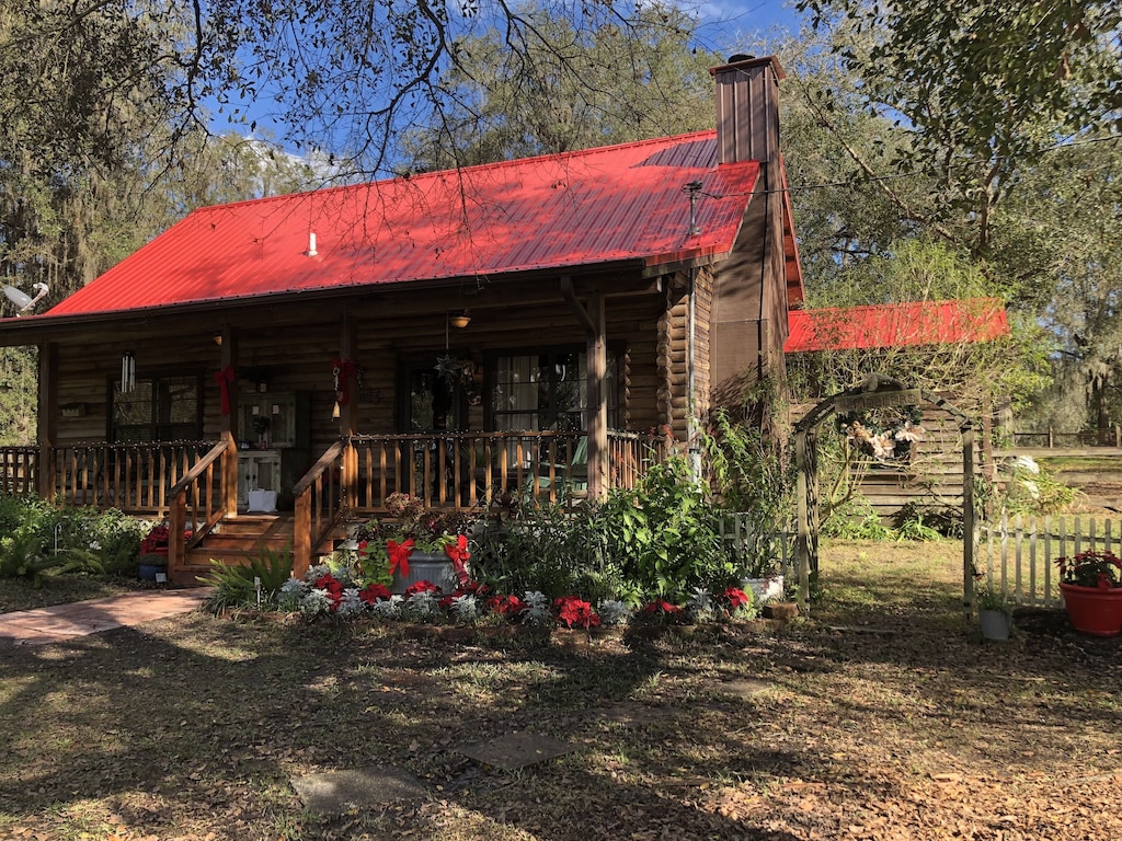 view of the red roofed log cabin and surrounding old growth oak trees 