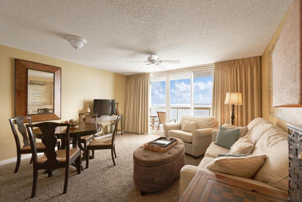 Pelican Pointe is where to stay in Destin: this golden hued living room has tables, couches, tvs, and a balcony perfect for relaxing. 