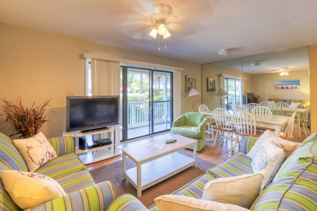 A tropical yellow condo features the prefect place to stay when considering where to stay in Destin: the striped couches, balcony, and long kitchen table are spacious! 
