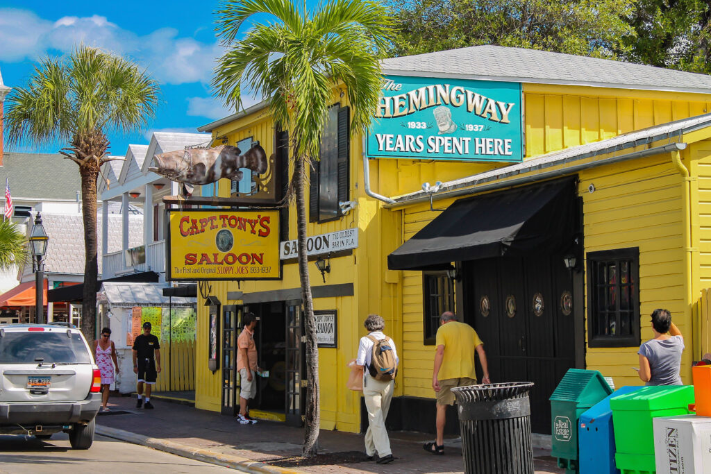 Yellow colored building with people passing by show oldest bar in Key West Fl