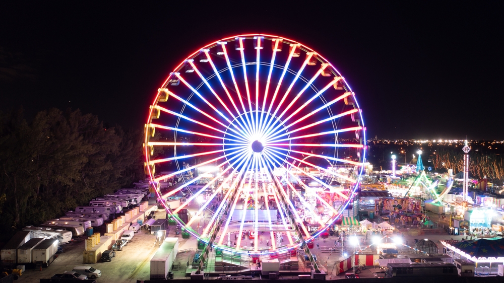 The ferris wheel at Santa's Enchanted Forest glows at night, surrounded by some of the best Christmas lights in Florida.