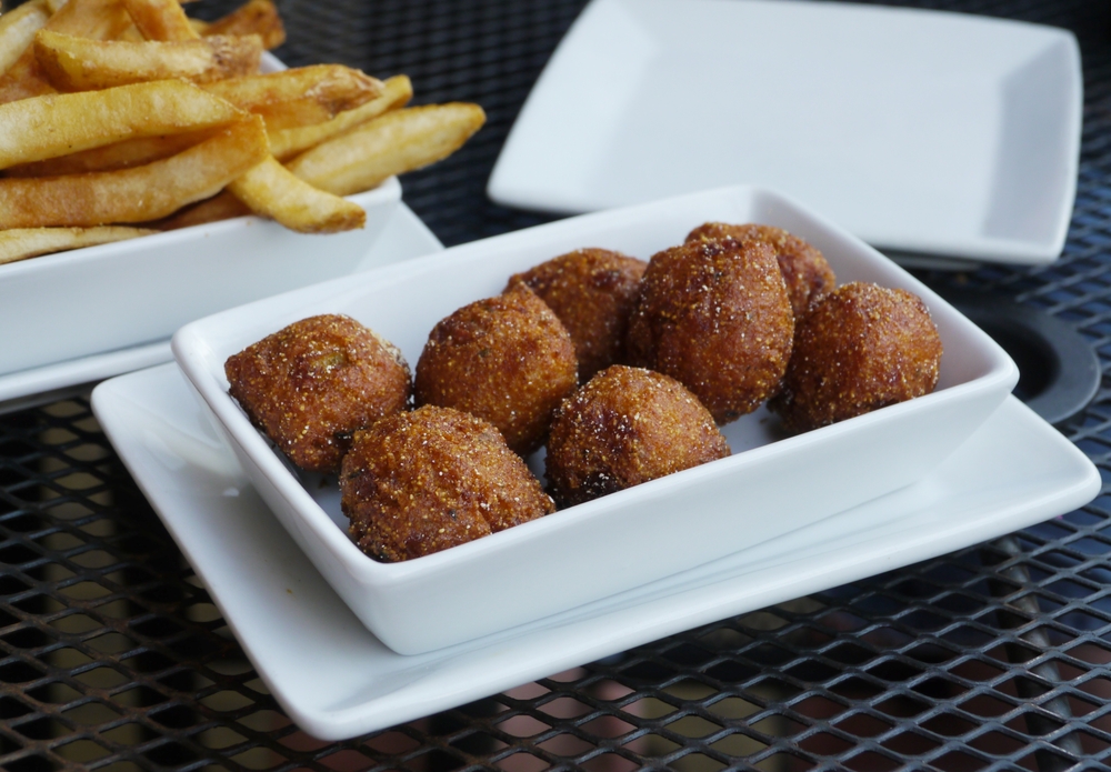 Eight round, fried hushpuppies sit on a white ceramic plate, with fries in the background, like those served at Burdines, one of the best restaurants in Marathon.