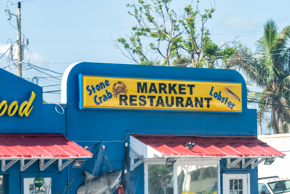 The blue exterior, red awning, and yellow signs of King Seafood, one of the more popular, affordable seafood restaurants in Marathon.