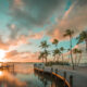 beautiful orange and teal sunset over calm waters and docks that stretch into the ocean decorated with palm trees!